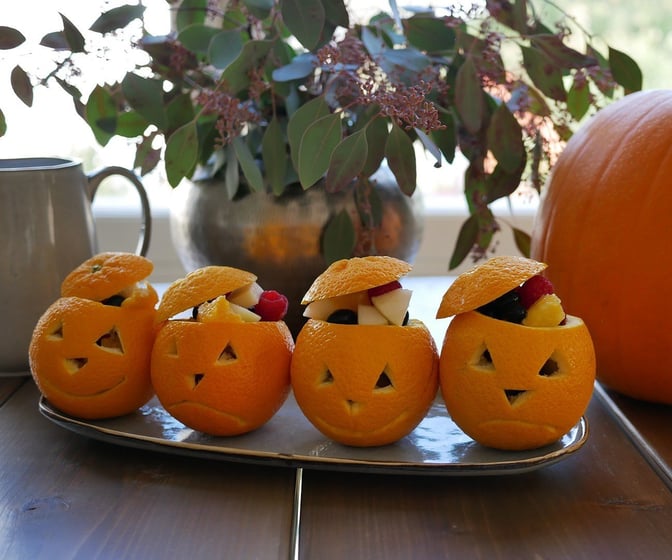Halloweenpumpor av apelsiner fyllda med fruktsallad